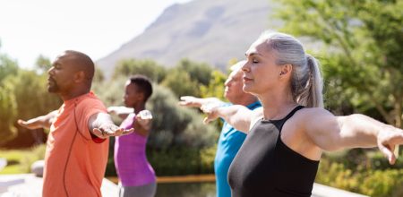Mature group of people doing breathing exercise Group of senior people with closed eyes stretching arms outdoor. Happy mature people doing breathing exercise near pool. Yoga class with women and men doing breath exercise with outstretched arms. Balance and meditation concept.